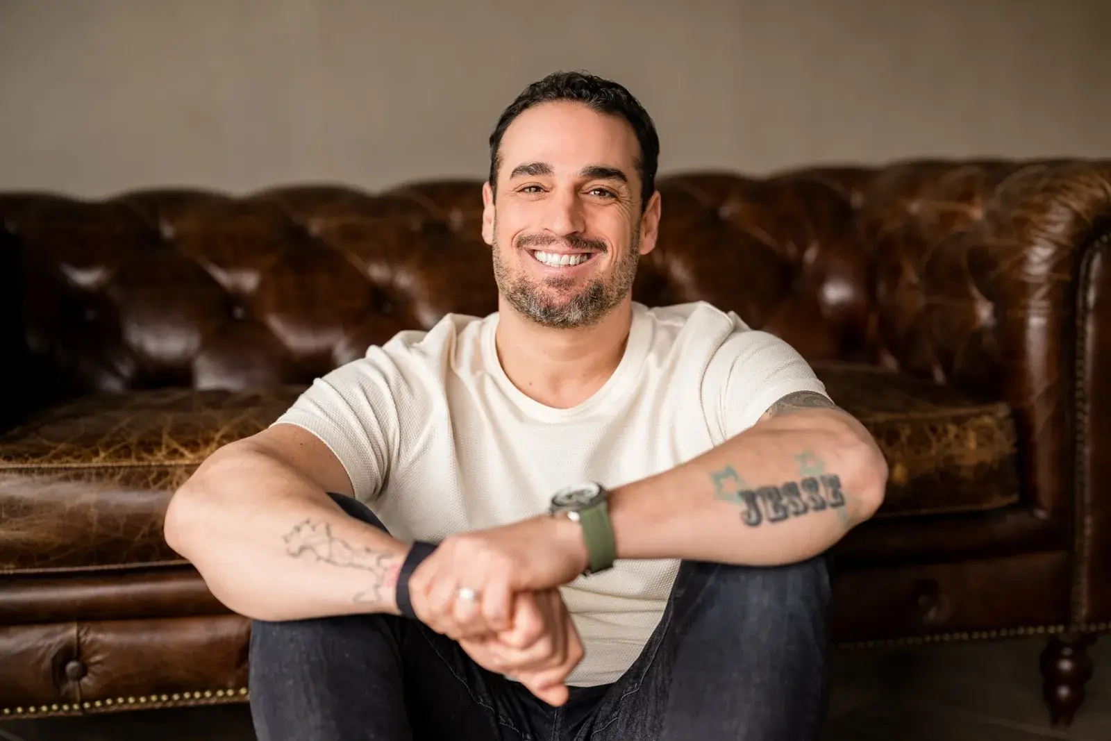 Johnny Suppa sitting on a leather couch, smiling